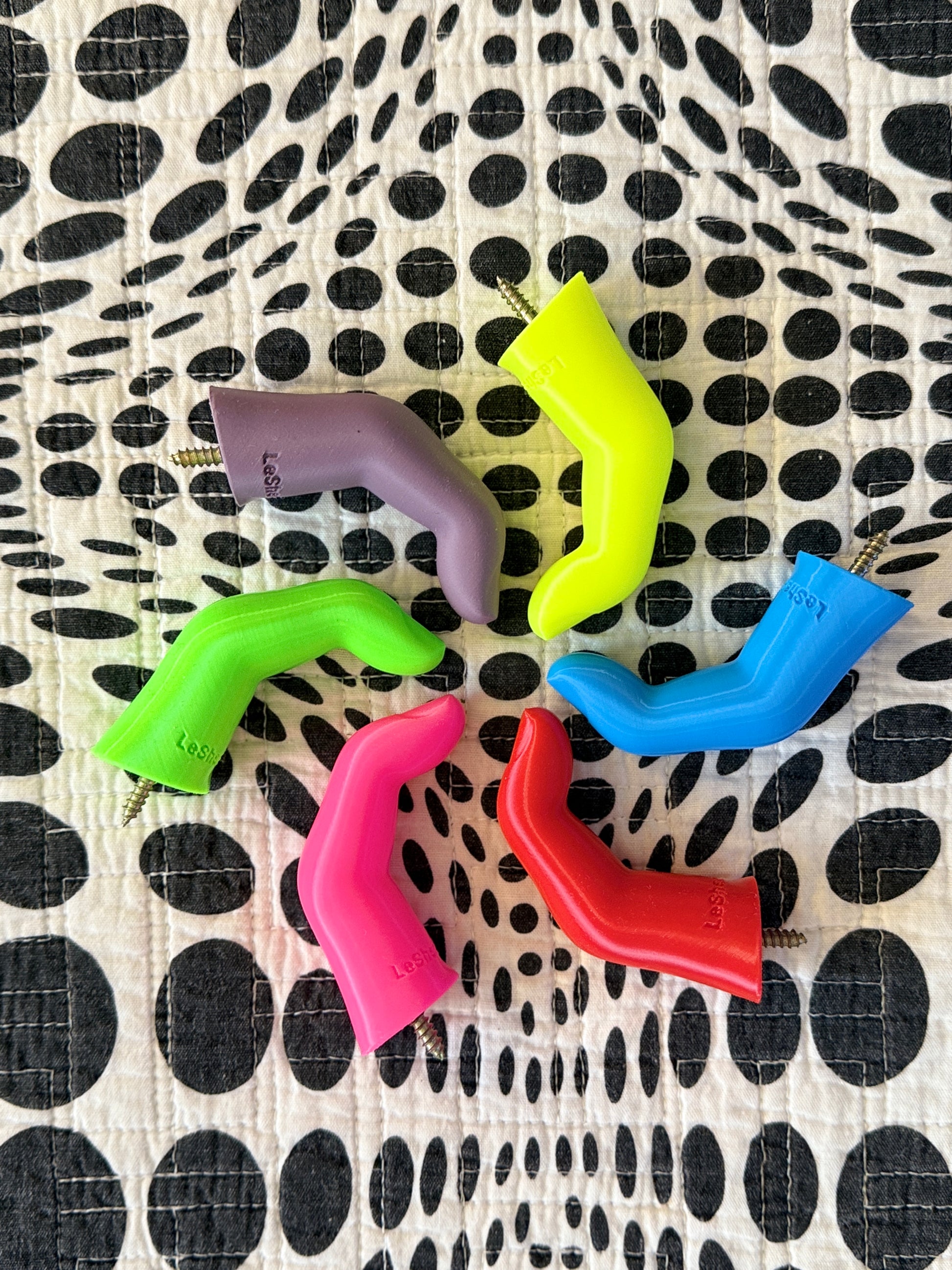 Colorful plastic finger shaped wall hooks on a black and white polka dot background