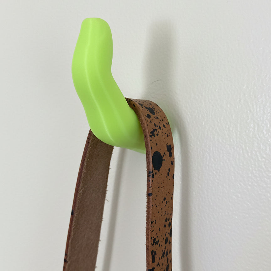 Neoln yellow finger hook holding a splatter leather purse strap